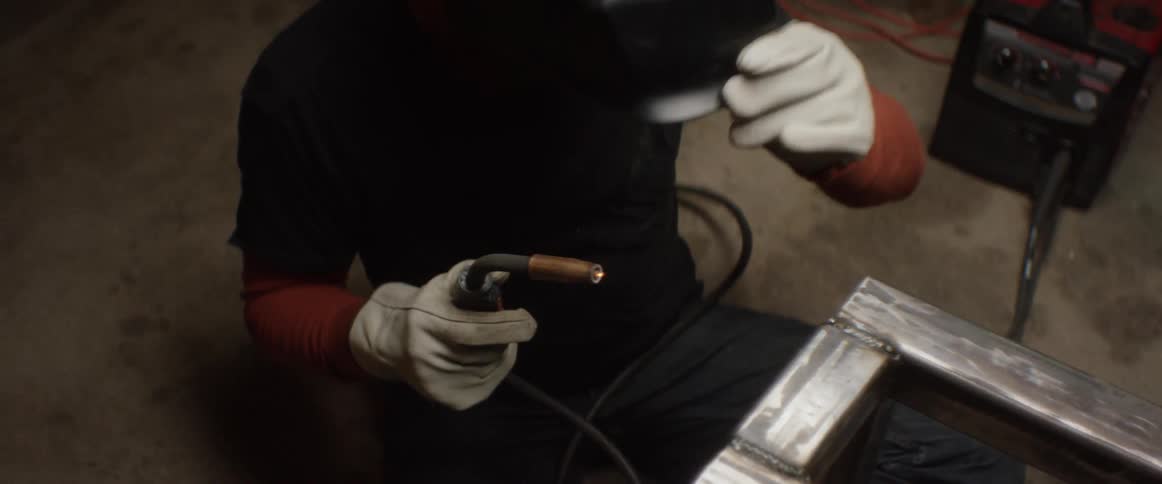 A welder lifts his mask