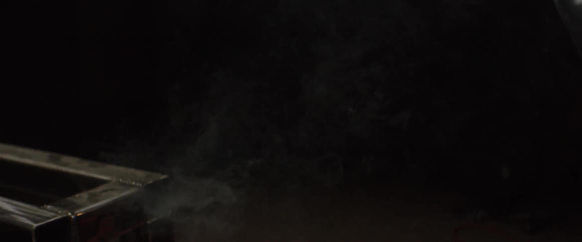 A man sits next to a metal structure in a dark room