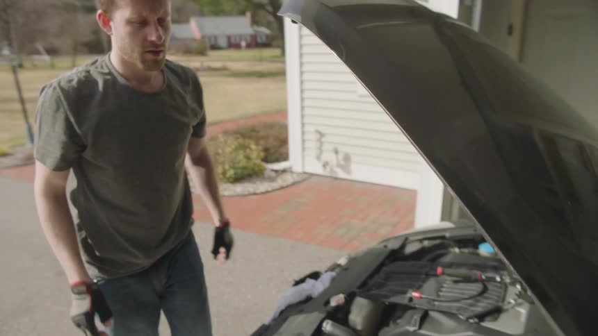 A man is working on the engine of a car
