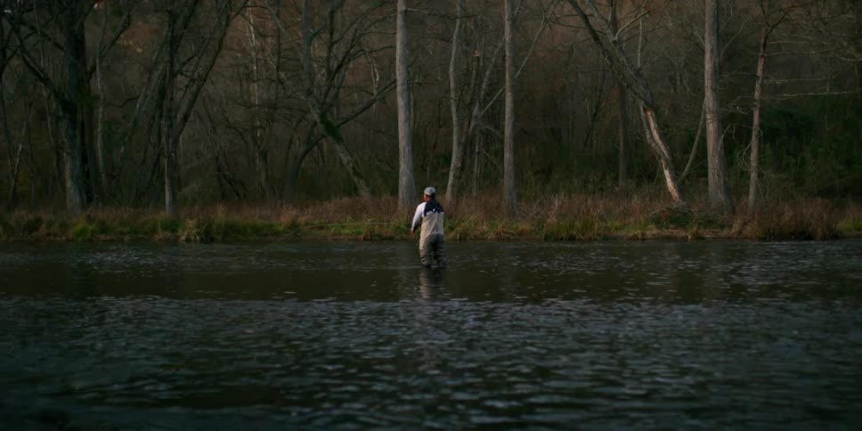 A man standing in a lake as he fishes
