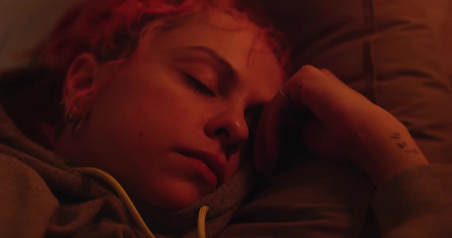 A woman with pink hair earrings and a hoodie sleeping