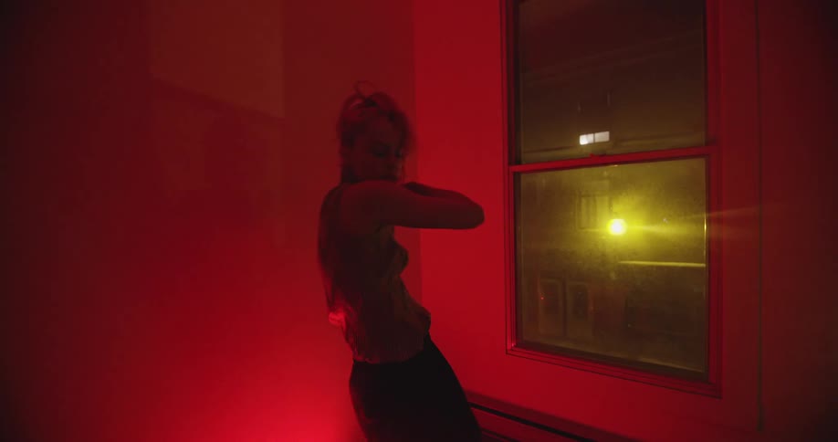 A teenage girl dancing inside at night