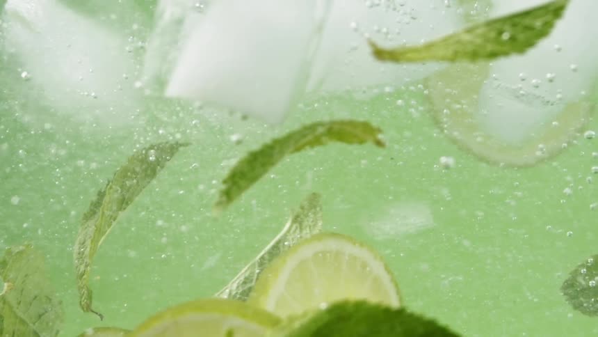 Limes swirling in liquid with mint and ice