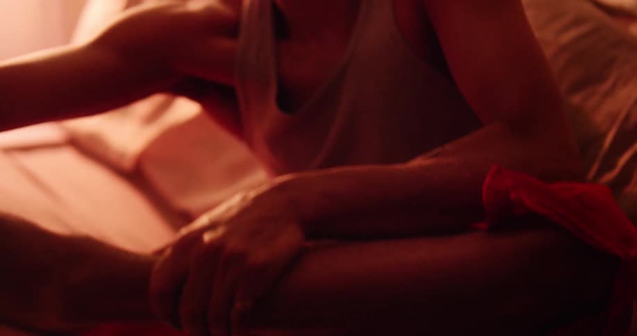 A man is sitting on a bed and putting on a shoe