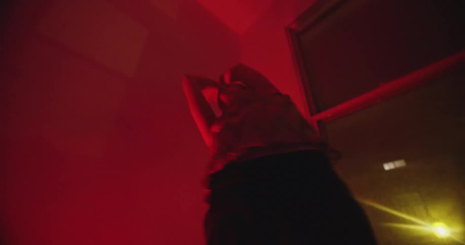 Woman with a ponytail dances wildly in a red lit room at night