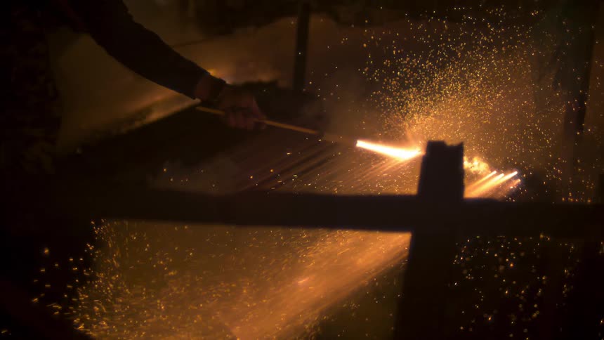 A man lights fireworks from a board at night