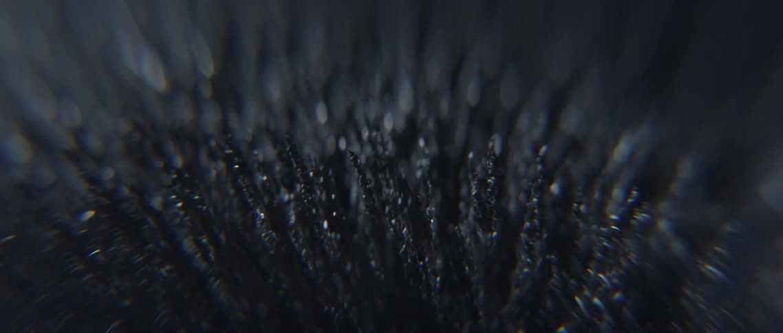 Small spikes of ferromagnetic powder protrude upwards and then flatten out as if attracted to a magnet