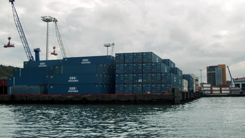 Shipping containers are stacked high and wide at a port next to the sea