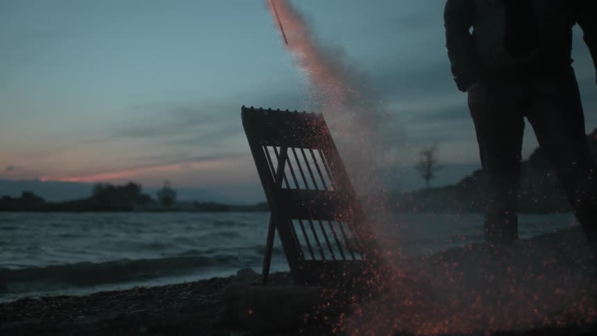 A lit fireworks rocket shoots into a dusk sky with the beach in the background