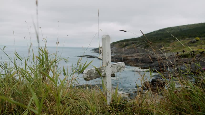 Wooden cross in the grass on the hills near the ocean