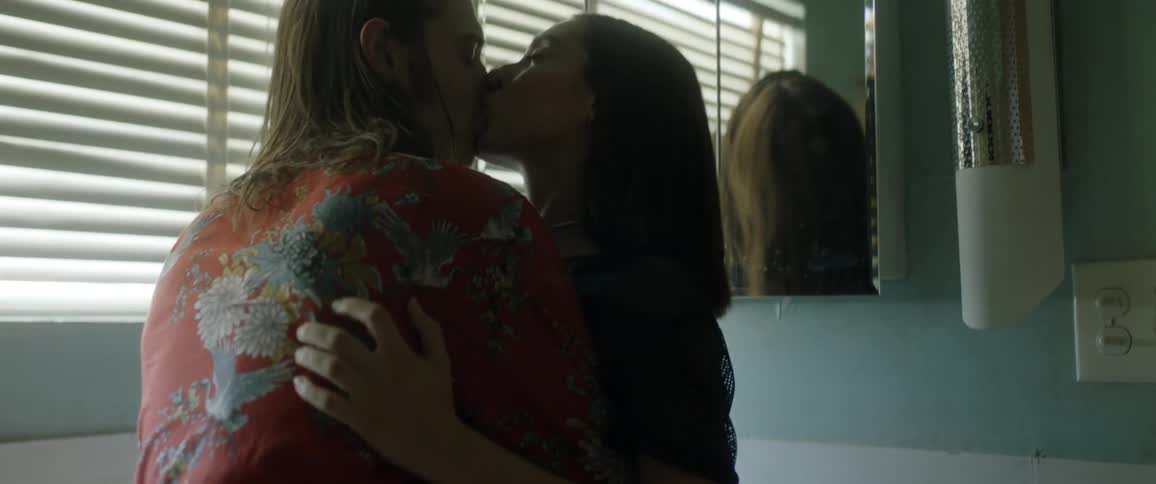 Young couple kisses passionately in front of mirror in bathroom