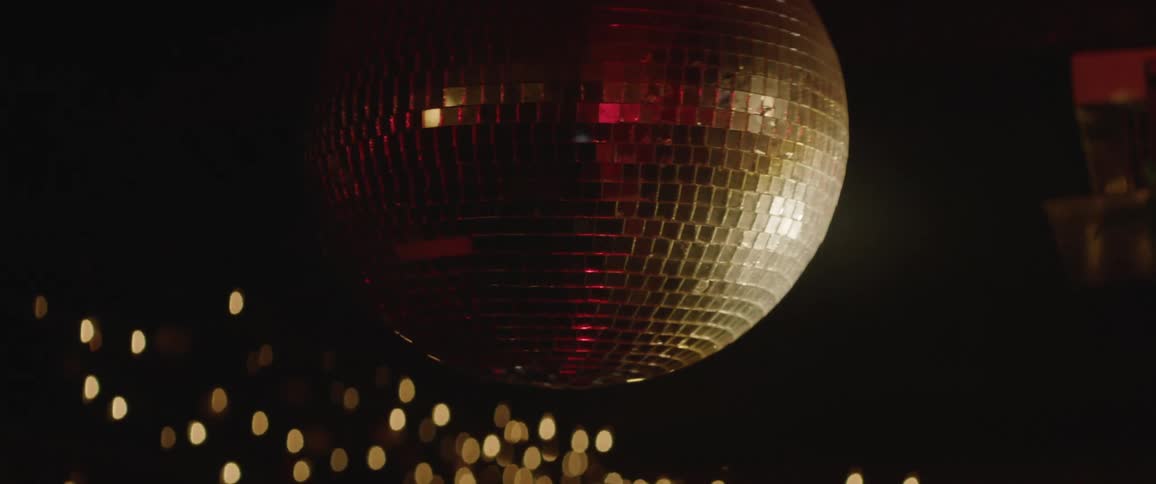 A mirrored disco ball spins and reflects light in a bar