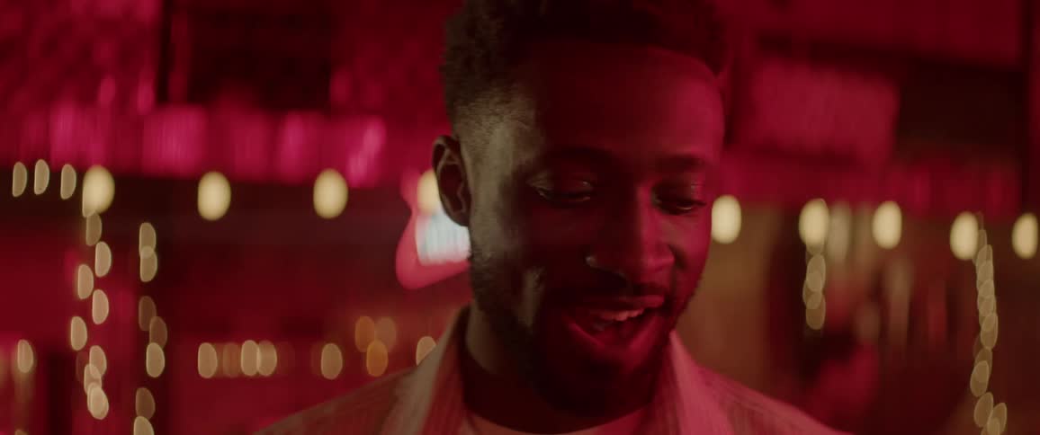 Man walks into focus, smiles then looks down and bites lip