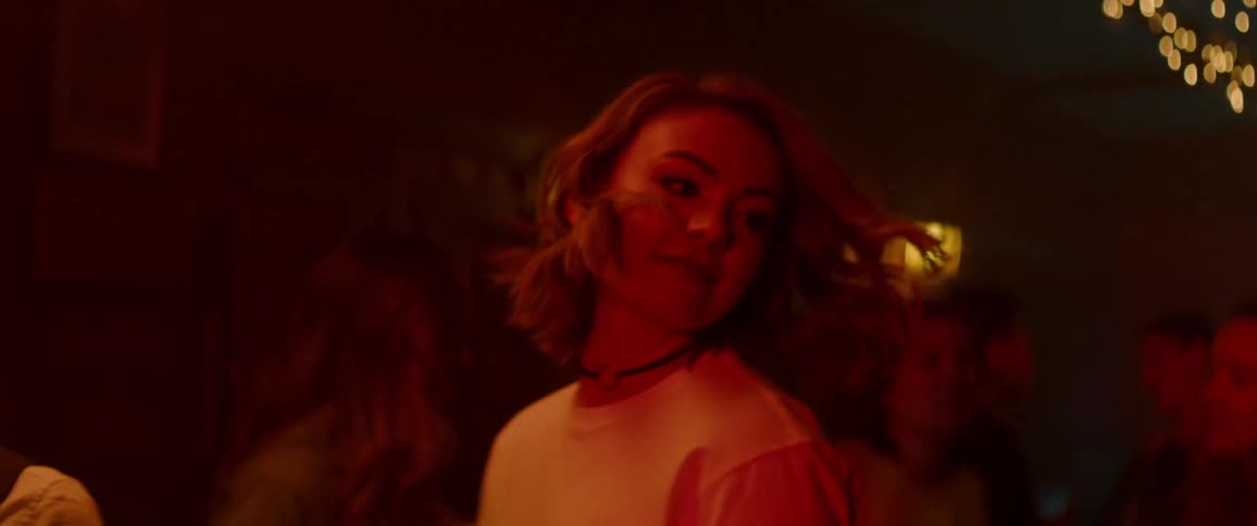 A young woman dances at a large party