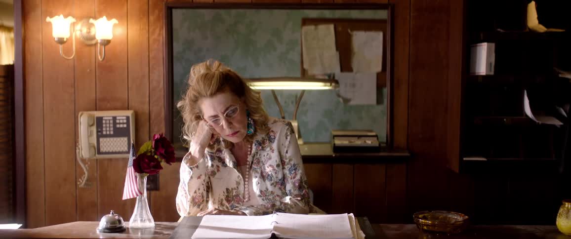 An old woman asleep at the front desk of a dated mote