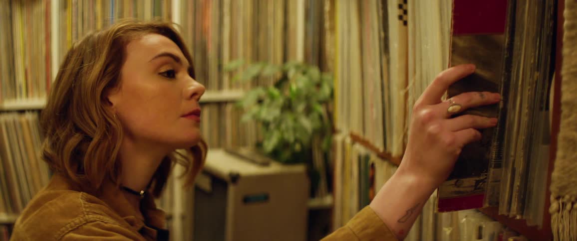 A young woman looking through the shelves of a large collection of vinyl records