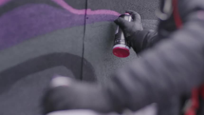 A person is spray painting a mural on a wall