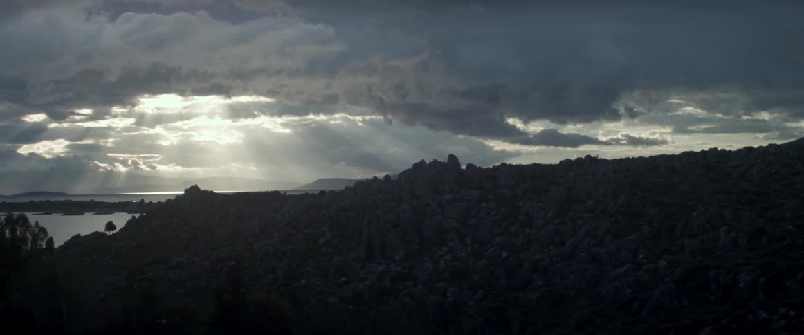 The sun shines down onto a rocky cliff