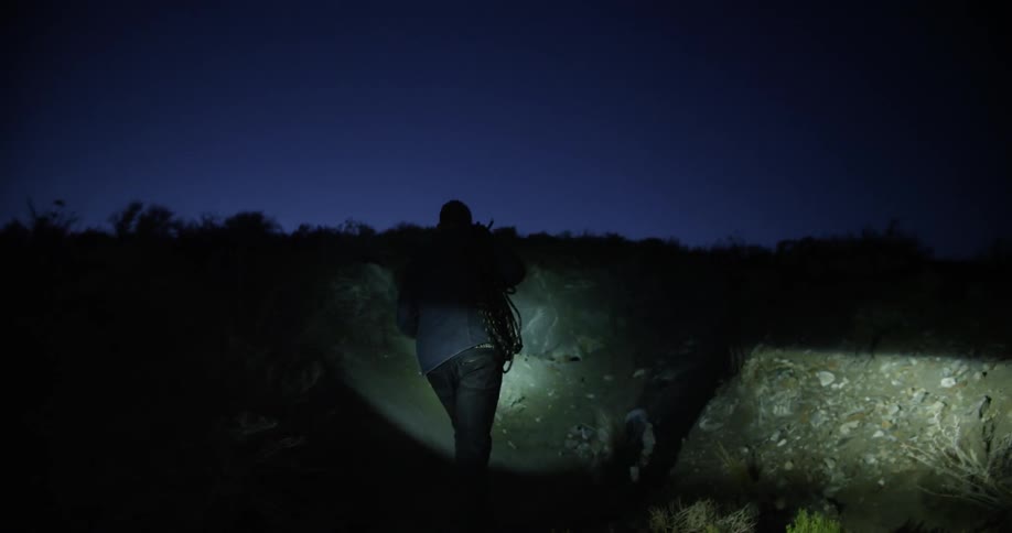 A man with a flashlight walks away from his vehicle