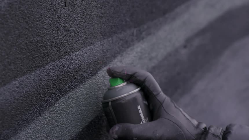A person is spraying a wall with spray paint