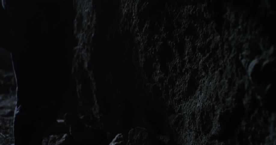 A person is walking barefoot in a dark cave