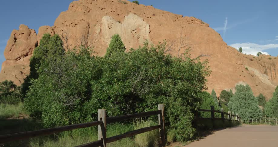 A small trail has a wood fence with a mountain behind it