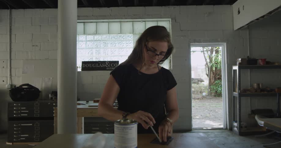A woman applying something to an item on a bench
