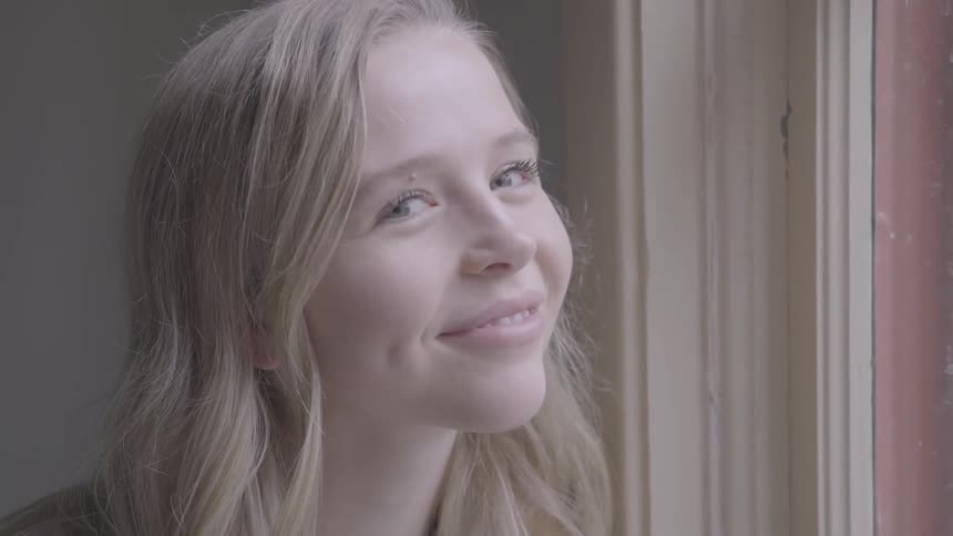 A girl smiles as she looks out a window