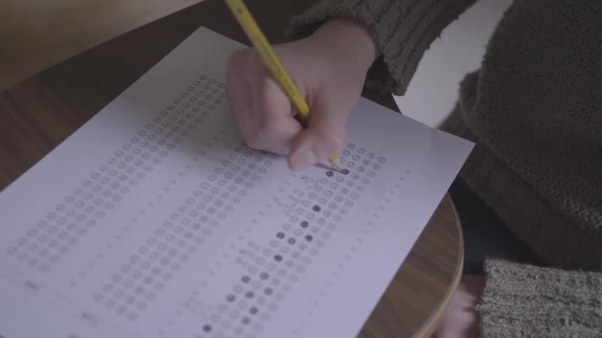 A girl fills out a multiple choice sheet at school