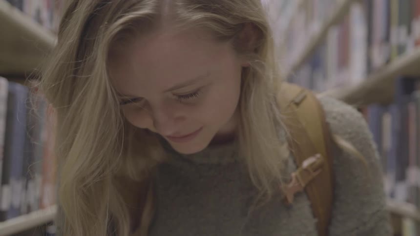 A teen female reading in the library
