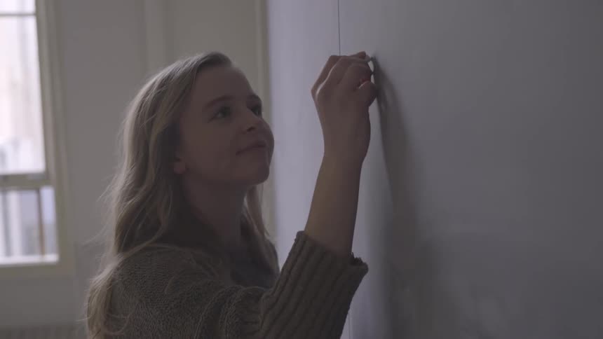 A girl writing on a chalkboard in a classroom