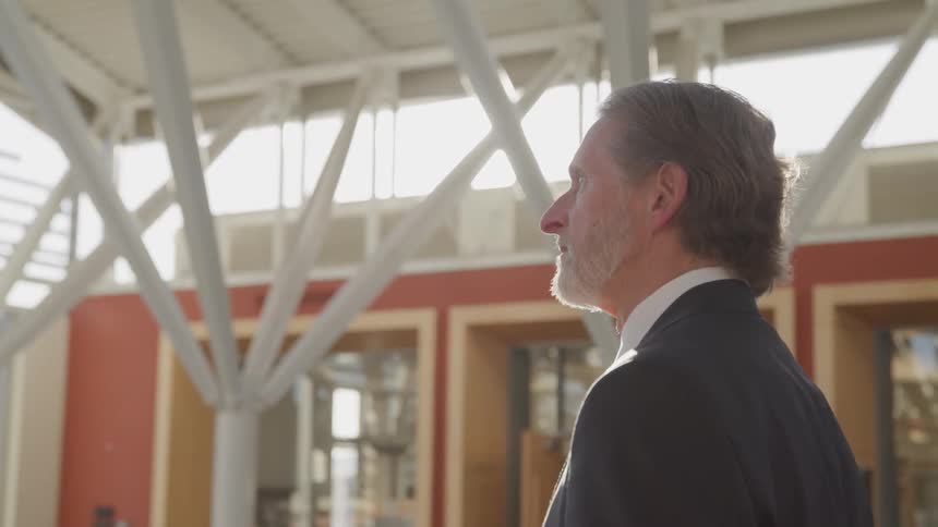 Side view of a businessman with a grey beard as the sun shines through the windows in a building