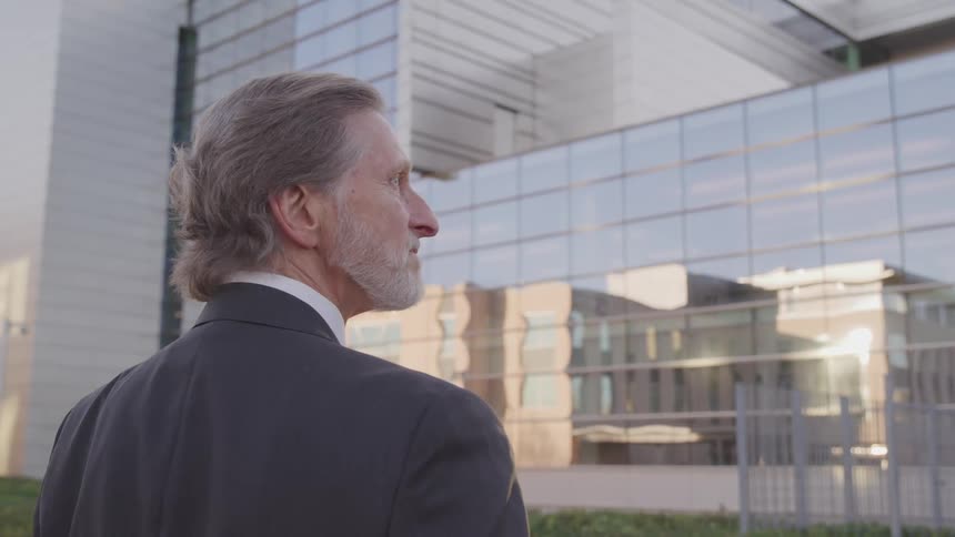 A businessman standing outside an office building in deep thought