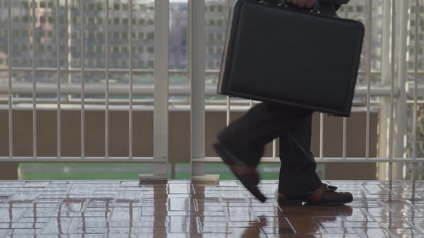 A man is walking in a building while holding a briefcase