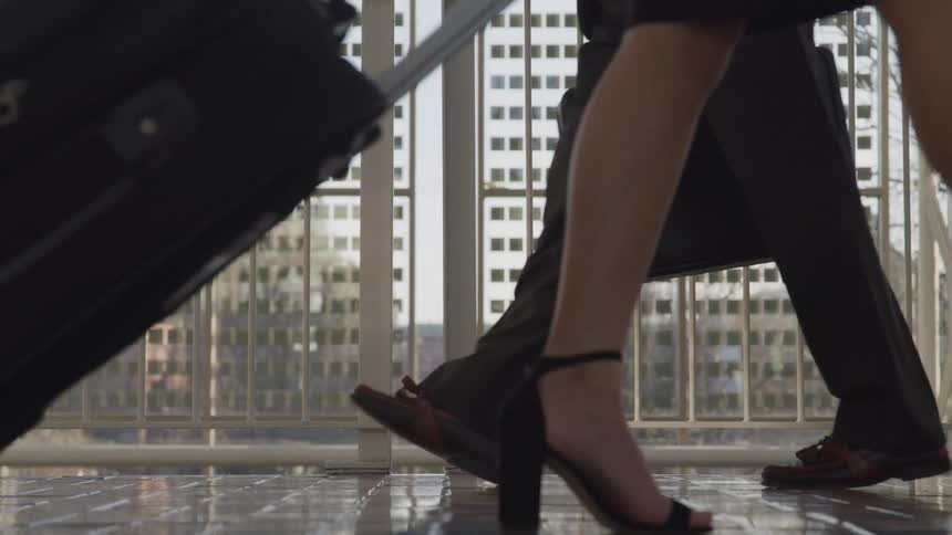 Man and woman pass each other with their luggage