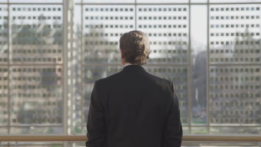 A man looking out the window of an office building