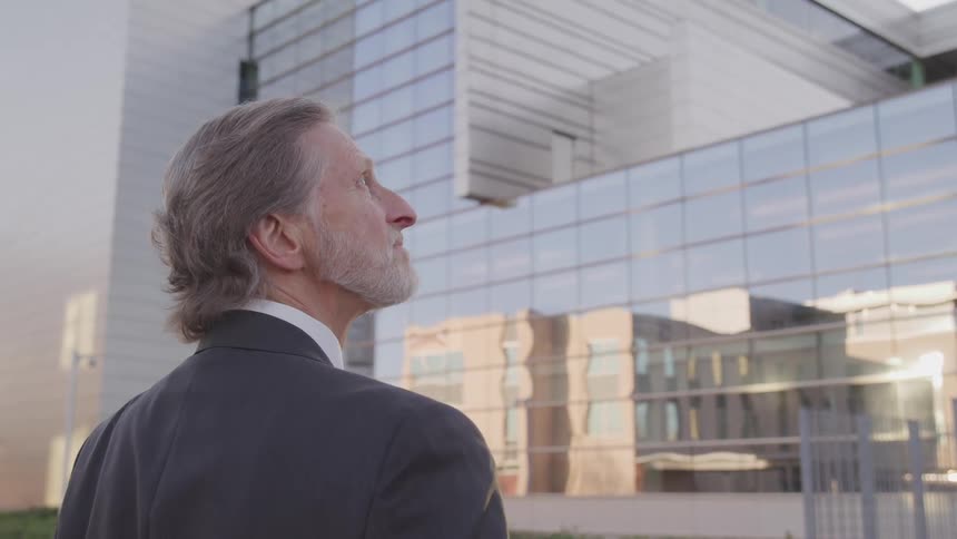 A man in a suit is looking at the large building