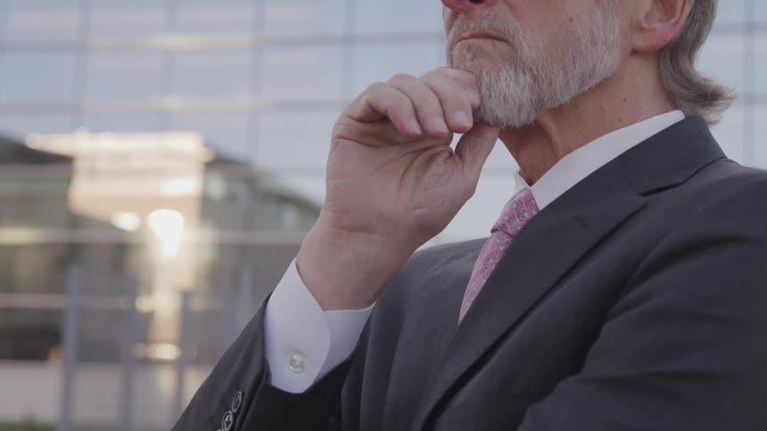 A man in a suit stands outside of an office building