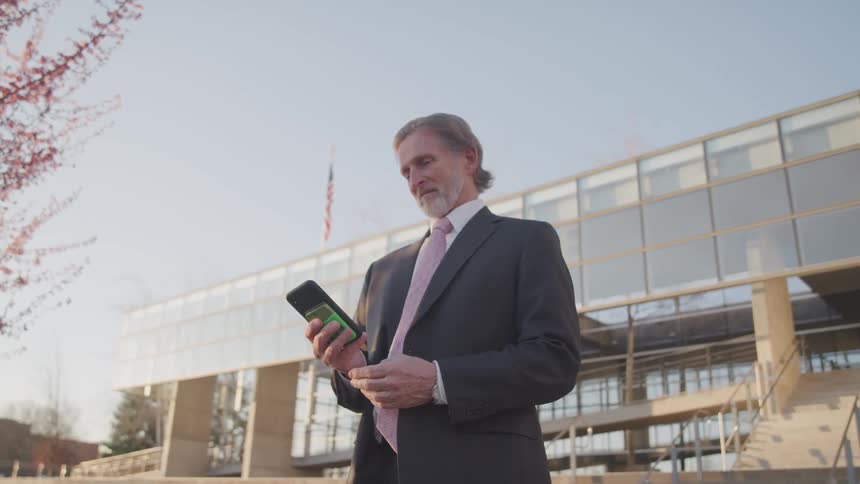 A businessman standing outside texting on his phone