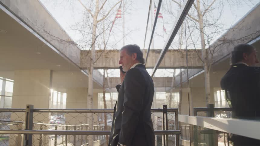 A businessman talks on a smart phone on a terrace outside