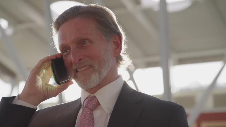 A man is standingo outdoors and talking on a cellphone