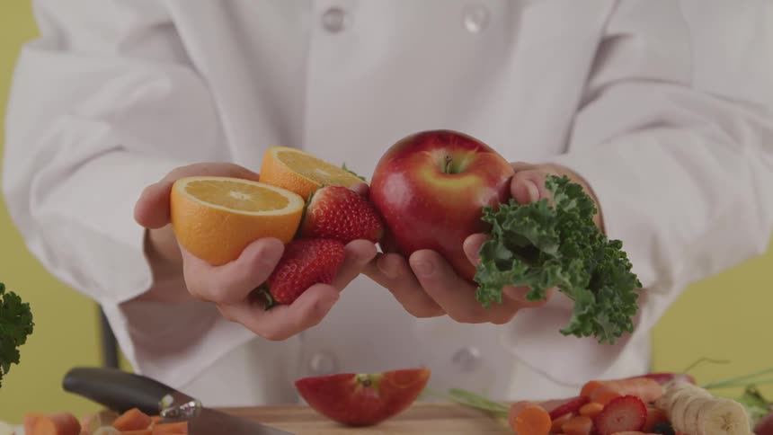A chef is holding fruits and vegetables