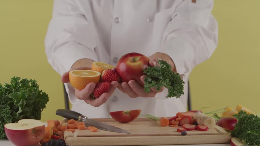 A man holding fruits and vegetables extends his arms