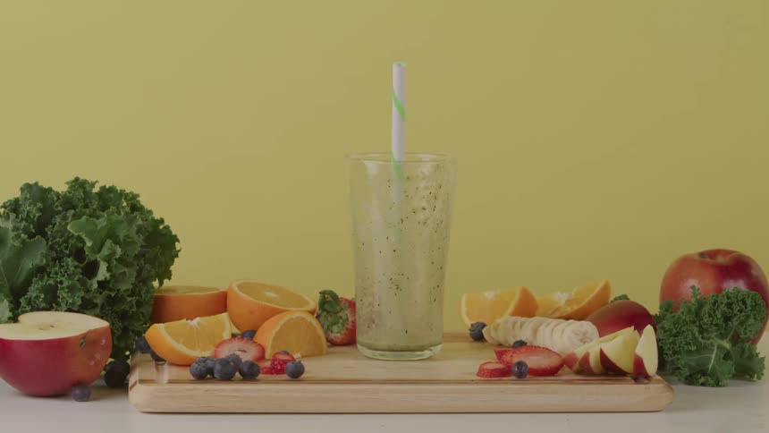 A person places glass that used to contain a fruit smoothie back onto a cutting board