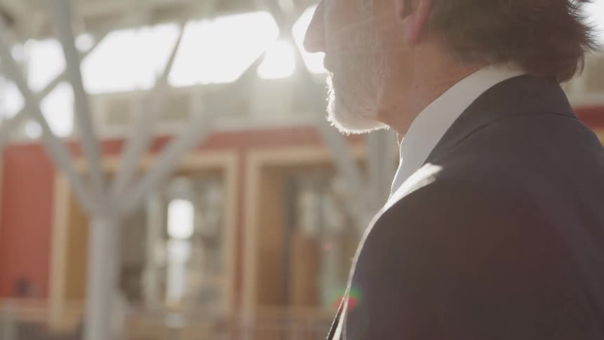 A man in a suit stands in an office building