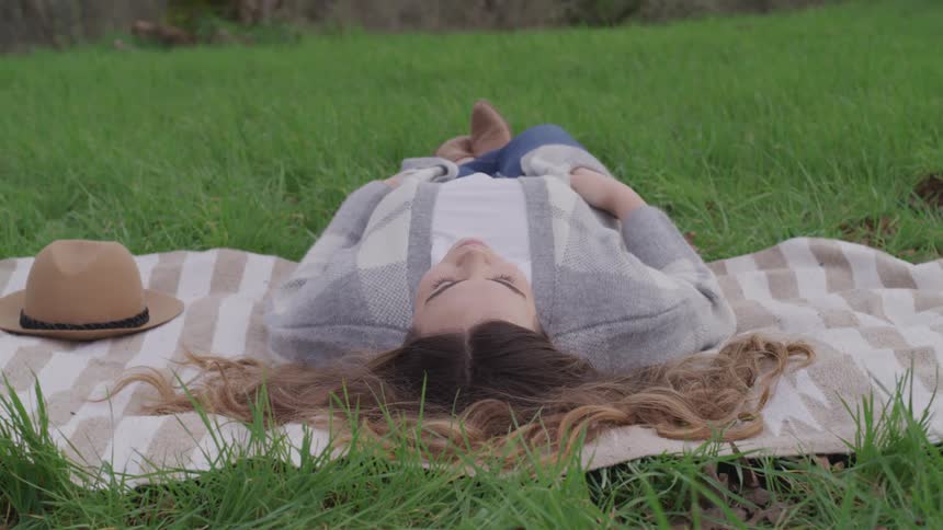 A teenage girl naps outside on a lawn