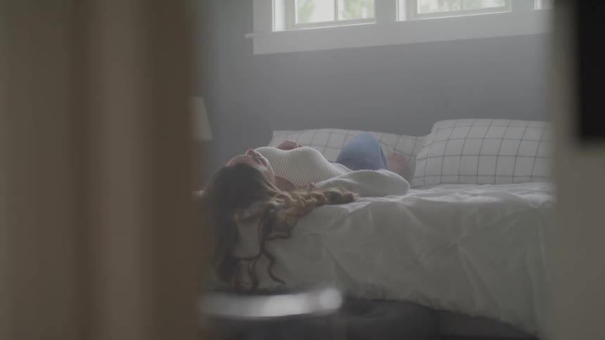 A teenage girl lying on her bed at home