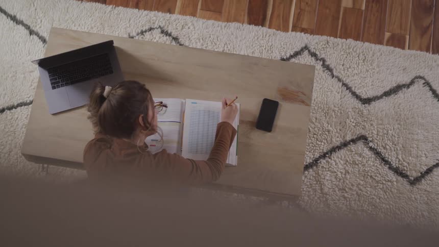 A teenage girl at home does school work at a desk