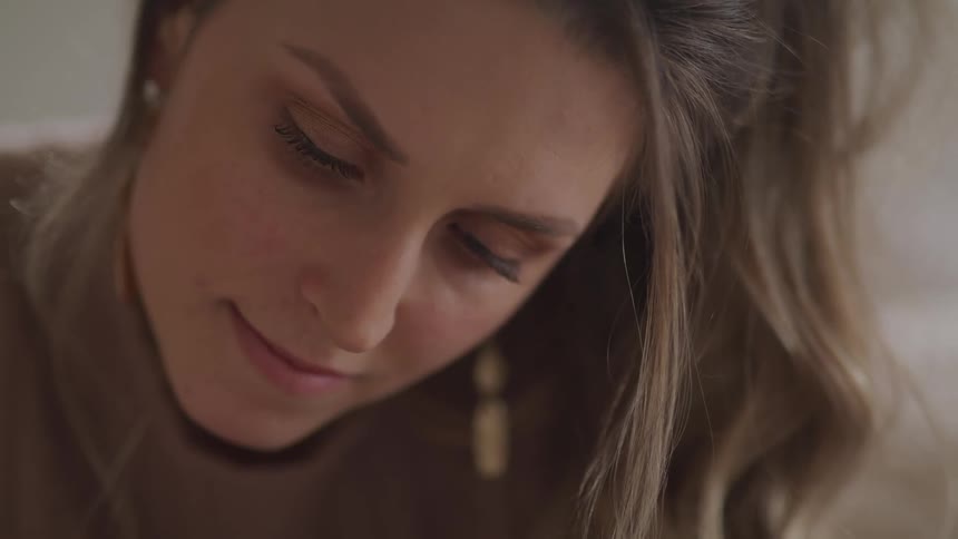 Woman with brown hair and a sweater looks down