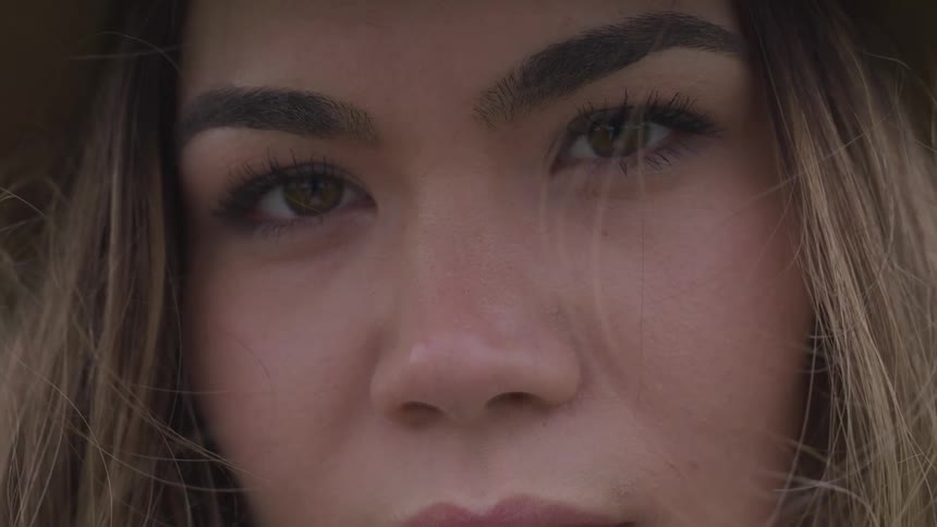 Woman stares and blinks as air stirs her hair